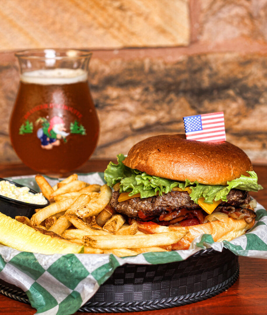 A hamburger and fries on the table with a glass of beer.